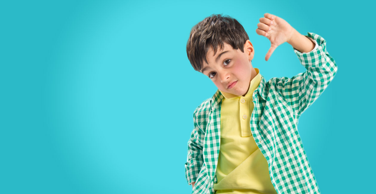 Boy standing with his thumb down.